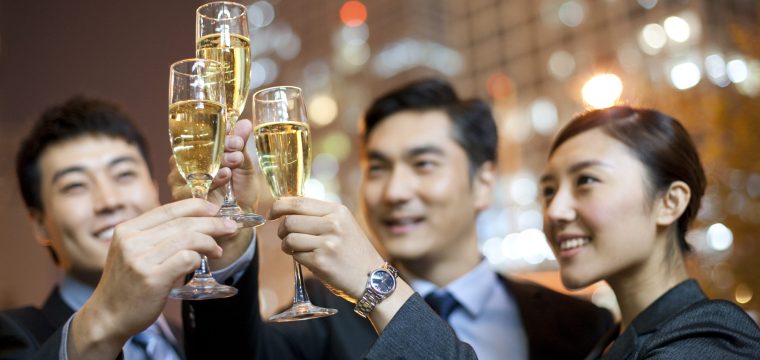 Chinese business people toasting champagne with city lights in the background